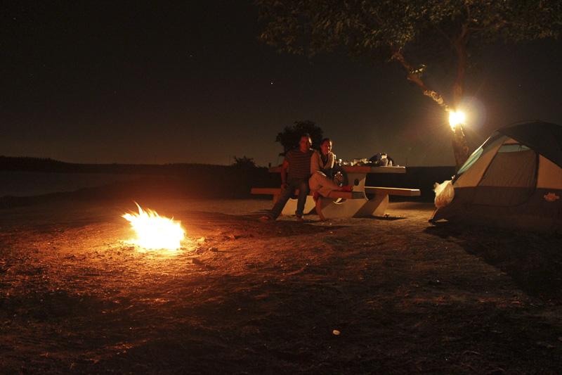 pareja acampando sentados alrededor del fuego