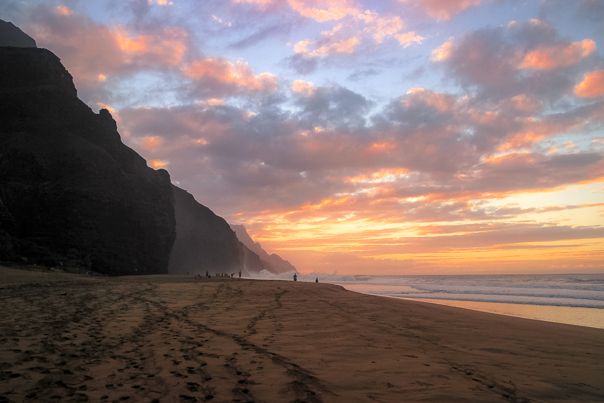 mujer caminando en una playa rodeada de gigantes picos y vegetacion selvatica