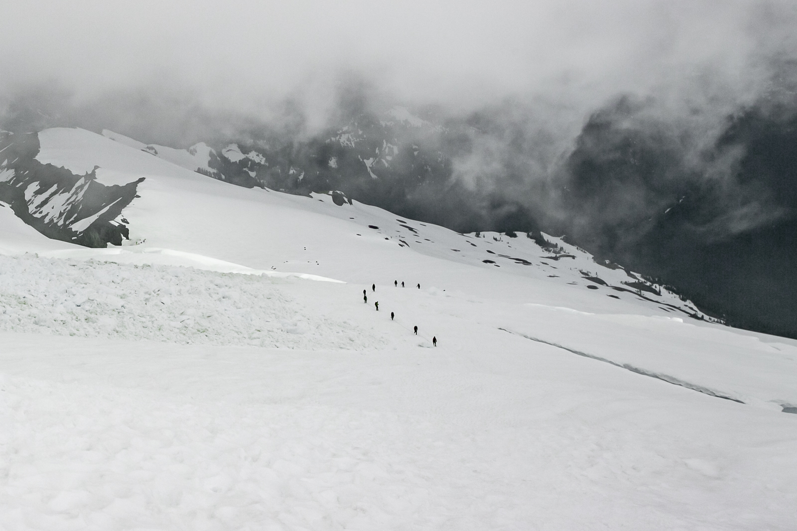 Mount baker cubierto por neblina y escaladores caminando